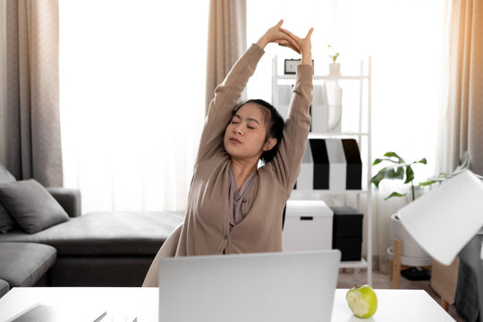 Young woman stretching after working laptop at home.