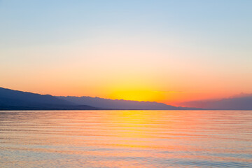 Obraz premium Dawn of the sun at sea. The rising sun behind the mountains. Kyrgyzstan.
