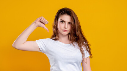 Dislike gesture. Bad idea. Portrait of dissatisfied unhappy woman in white t-shirt rejecting with...