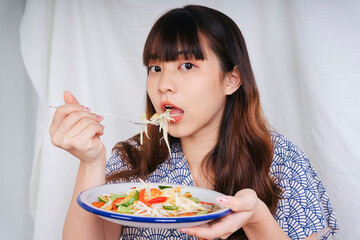 Young asian woman eating papaya salad Isand food with fork.