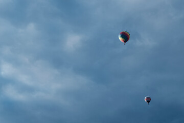 one multicolored balloon flies high in the sky covered with clouds