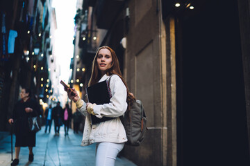 Content modern female student texting on street