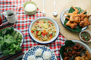 Set of Isan food on table with papaya salad, grilled chicken, rice noodle, spicy mince pork and vegetables.