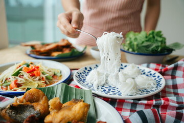 Hand of woman eating rice noodle with fork.