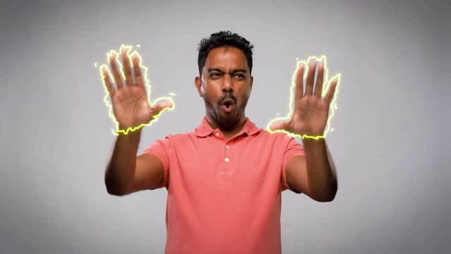 people concept - smiling young indian man making faces and different gestures with movements over grey background with animated glowing lines