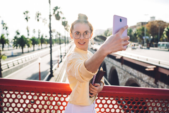 Young female student taking selfie on bridge