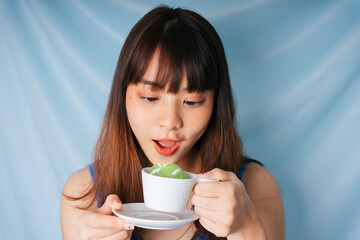 Asian dark hair woman eating sweet green sticky rice.