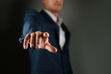 The man holds his index finger in front of him. A man in a suit points a finger forward on a black...