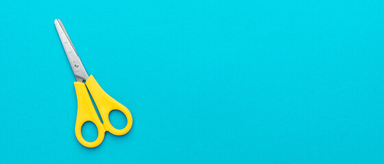 Yellow scissors on the turquoise blue background. Flat lay image of scissors with copy space. - obrazy, fototapety, plakaty