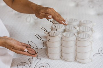 Mattress spring in the hands of a woman. Pocket independent spring. The concept of filling a...