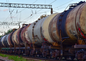 Fototapeta na wymiar Freight train with petroleum tank cars on railroad. Rail cars carry oil and ethanol. Railway logistics explosive cargo. Transportation of methanol, crude and gas. Petrochemical tank cars. Out of focus