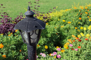 Beautiful lamp post in a garden with colorful flowers.