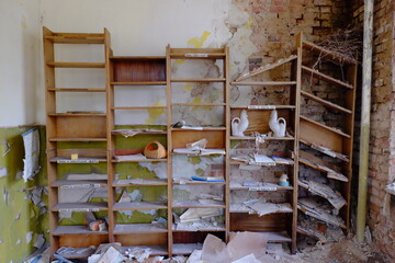 Old shelves for papers in an abandoned room. Rubbish and papers scattered around the room.