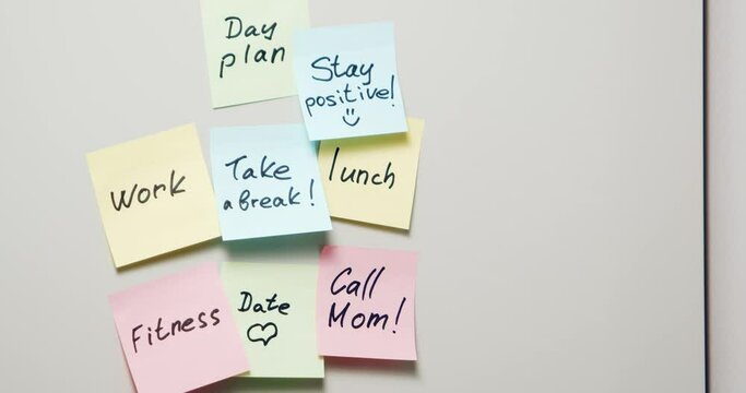 Close-up of multi-colored stickers with notes written with a marker and pasted on a gray board. Day plan. Copy space. Background.