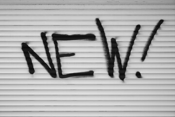 black word - NEW ! - with exclamation mark on white garage door background.