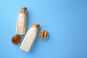 Bottles of vegan non dairy milk with various nuts on blue background