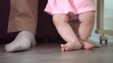 Infant feet learning walk. Parent support concept. Little steps at home