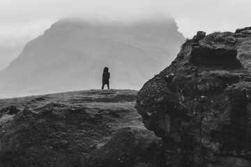Man alone on the edge of a cliff surrounded by mountains