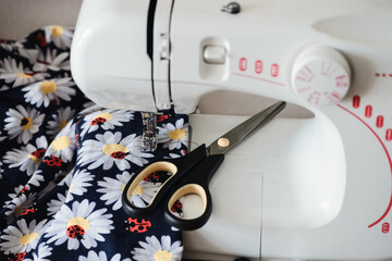 Multicolored textile and tailor scissors lay on sewing machine panel