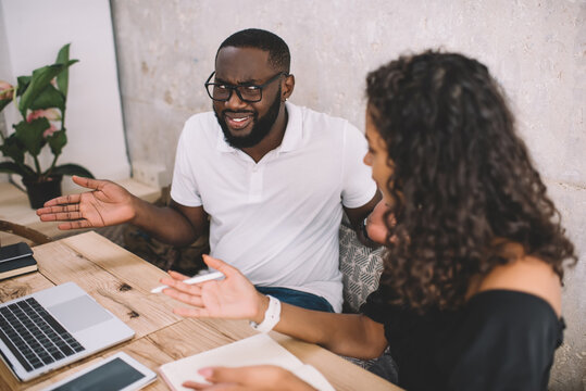 Dark skinned couple having quarrel while using laptop computer for online shopping gesture during conversation, african american woman and man colleagues discussing cooperation having problem