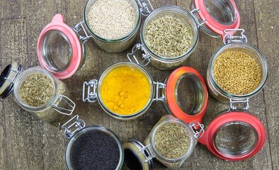 Top view on isolated preserving jars with variety of colorful condiments on wood table