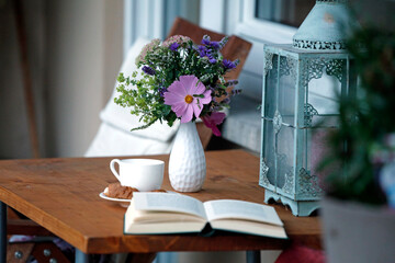 Urlaub zuhause auf Balkon mit Kaffee, Buch, Gebäck, Blumenstrauss