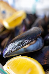 Macro close up of a serving of steamed mussels with slices of fresh lemon. Fresh seafood in seafood restaurant in Italy. italian recipe and specialty.