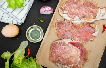 Fresh meat. Raw pork steak with spices.Top view on black background