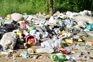 A large number of accumulated plastic bags and plastic packaging of household waste in garbage containers. The problem of garbage removal from the village, the concept of environmental pollution