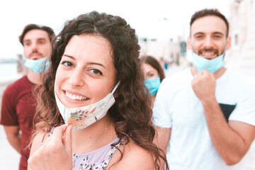 Group of friends smile with surgical mask - hope and return to normal after lockdown of coronavirus...