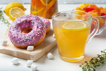 Delicate strawberry doughnuts with sugar sprinkles for a tea break. Summer fruit tea with herbs, honey and lemon. Marmalade from lemon juice, grapefruit.