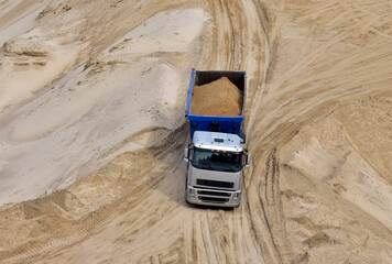 Truck with tipper semi trailer transported sand from the quarry. Dump truck working in open pit mine. Sand and gravel is excavated from ground. Mining industry