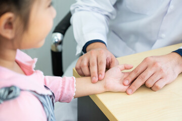 doctor checking radial pulse of young asian girl who visit at hospital clinic. healthcare and medical concept