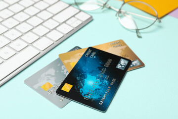 Credit cards near computer keyboard on light blue background