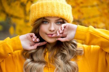 Beautiful woman walking outdoors in autumn. Smiling woman collects yellow leaves in autumn. Young woman enjoying autumn weather.