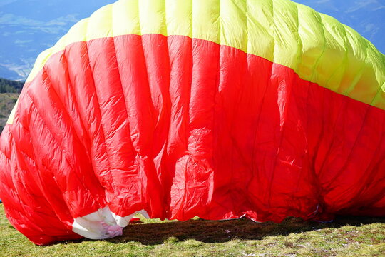 Red and yellow parachute of paragliders opening for the jump