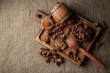 Dried chanterelle mushrooms (Cantharēllus cibārius), on a wooden board, on a rough woven background, burlap, top view