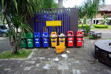 the multi color plastic bin in the park with garbage on cement ground