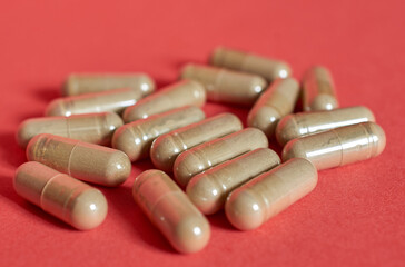 Medicine in capsules scattered on a red background