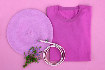 Fashion flat lay clothing. Lilac beret color, belt, folded jacket on a pink background.