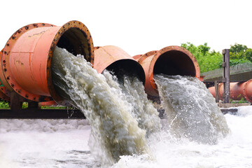 dirty sewage or waste water gushing from orange rusty metal big pipe