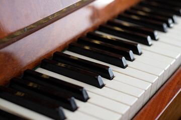 The keyboard of a brown upright piano on a blurred background. Selective focus.