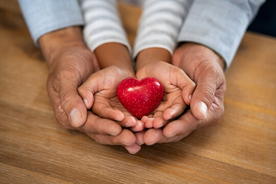 Man And Child Hand Holding Red Heart Stone