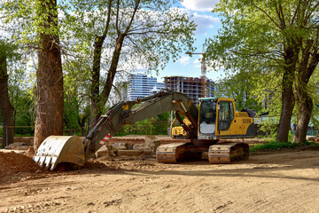 Excavator working at construction site on earthworks. Backhoe digging building foundation and paving out sewer line. Construction machinery concept