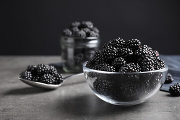 Fototapeta na wymiar Delicious fresh ripe blackberries in glass bowl on grey table. Space for text