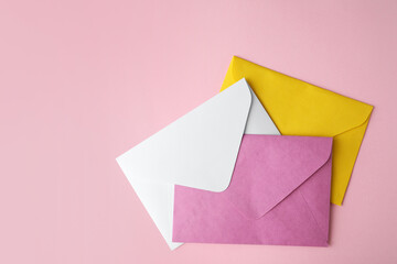 Colorful paper envelopes on pink background, flat lay