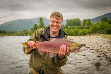 A happy fisherman proudly holding up a sockeye salmon