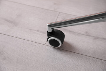 Modern office chair with wheel on wooden floor, closeup