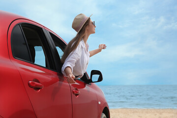Naklejka premium Happy woman leaning out of car window on beach. Summer vacation trip
