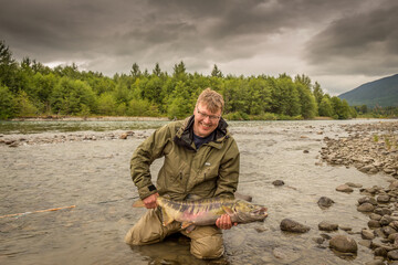 A happy sport fisherman holding up a big trophy Chum Salmon